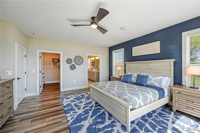 bedroom with dark wood-type flooring, ensuite bathroom, ceiling fan, a spacious closet, and a closet