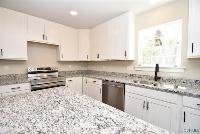 kitchen featuring recessed lighting, a sink, white cabinets, appliances with stainless steel finishes, and light stone countertops