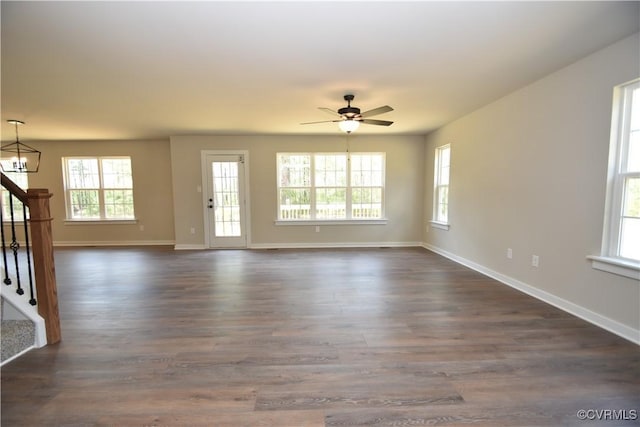 unfurnished living room with dark wood-style floors, a wealth of natural light, and stairs