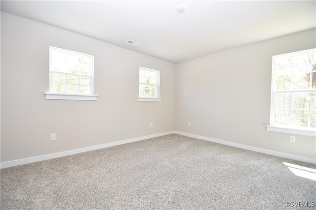 carpeted spare room with visible vents and baseboards