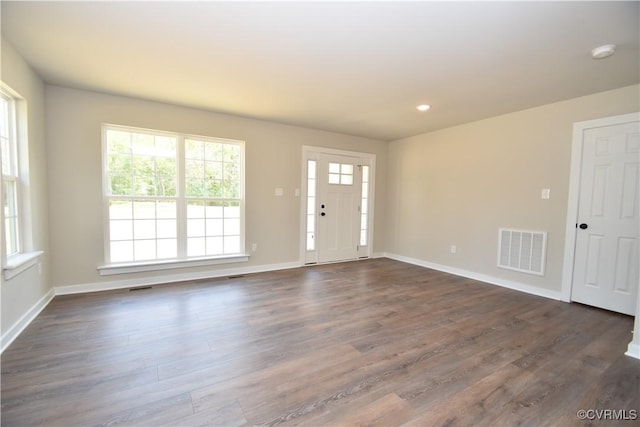 foyer entrance featuring dark wood-style floors, visible vents, and baseboards