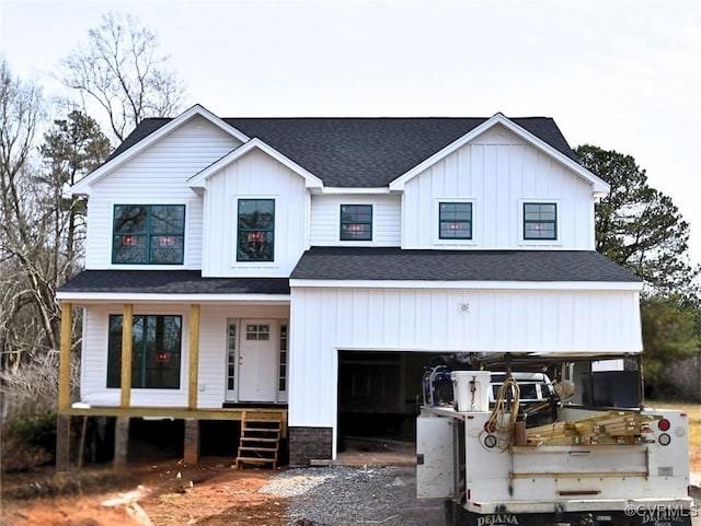 modern inspired farmhouse featuring a porch, an attached garage, a shingled roof, board and batten siding, and gravel driveway