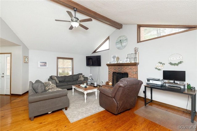 living room featuring hardwood / wood-style floors, lofted ceiling with beams, ceiling fan, a fireplace, and a textured ceiling