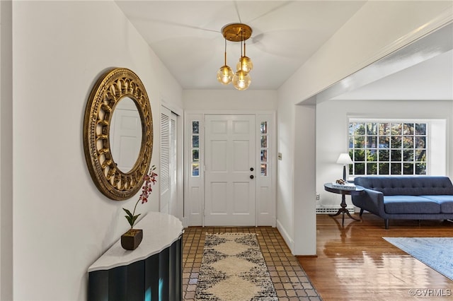 entrance foyer featuring hardwood / wood-style flooring, baseboard heating, and a notable chandelier