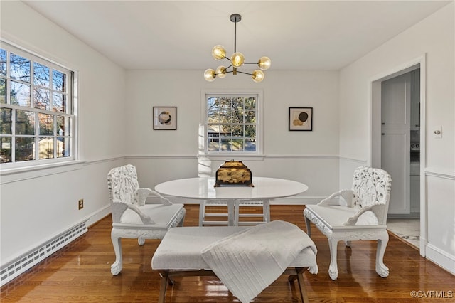 dining space with hardwood / wood-style flooring, breakfast area, a notable chandelier, and a baseboard heating unit