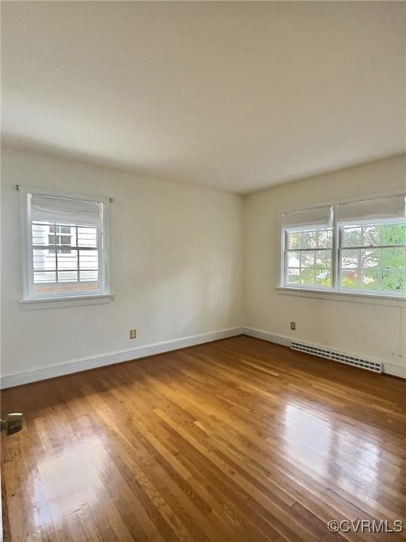 spare room featuring a baseboard radiator and hardwood / wood-style flooring