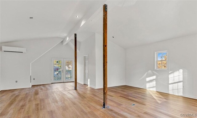 additional living space featuring a wall mounted air conditioner, a healthy amount of sunlight, french doors, and light hardwood / wood-style flooring