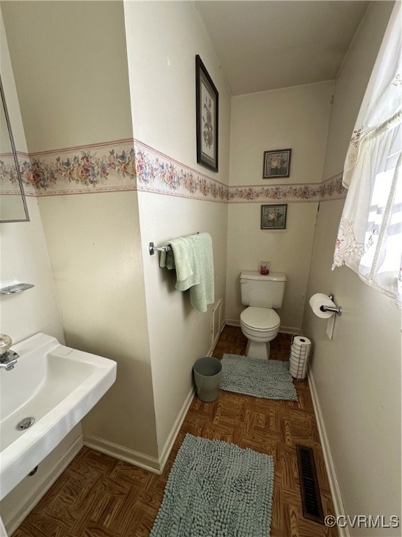 bathroom featuring parquet flooring and toilet