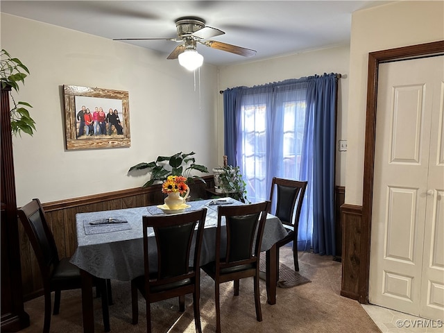 dining area featuring wood walls, carpet flooring, and ceiling fan