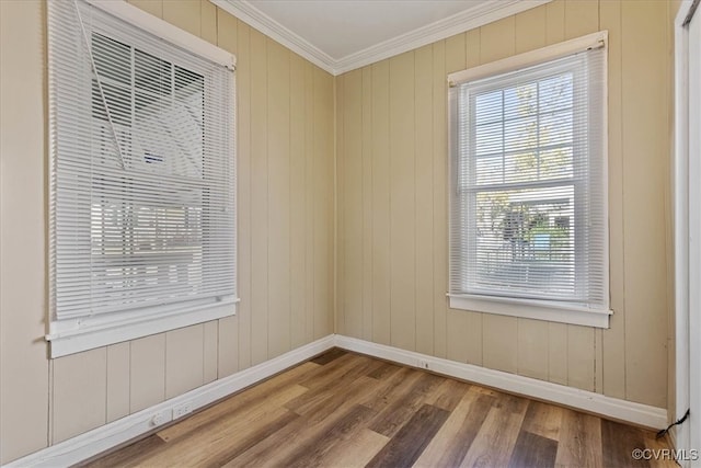 empty room featuring hardwood / wood-style floors, crown molding, and wood walls