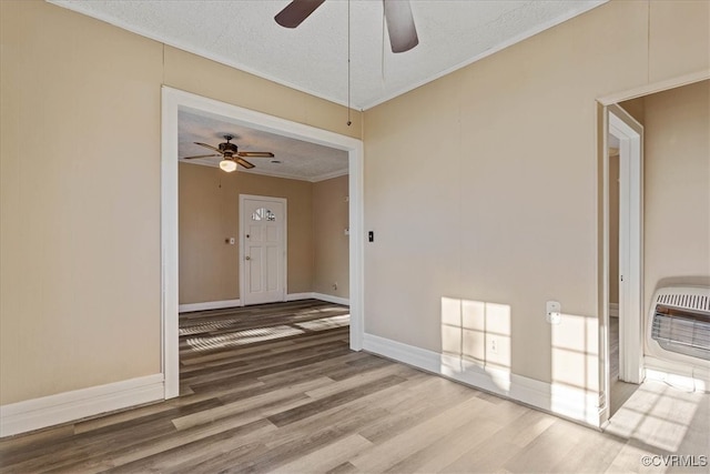 unfurnished room featuring heating unit, wood-type flooring, a textured ceiling, and ornamental molding