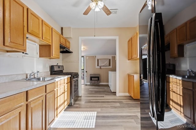 kitchen featuring washer and clothes dryer, ceiling fan, appliances with stainless steel finishes, light hardwood / wood-style floors, and heating unit