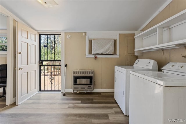 laundry area featuring light wood-type flooring, heating unit, and washer and clothes dryer