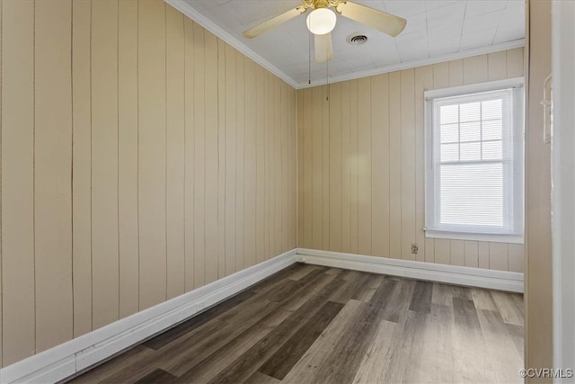 empty room with hardwood / wood-style flooring, ceiling fan, ornamental molding, and wood walls