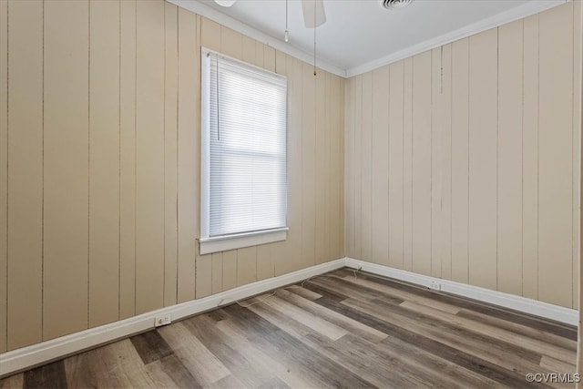 empty room with hardwood / wood-style floors, plenty of natural light, and crown molding