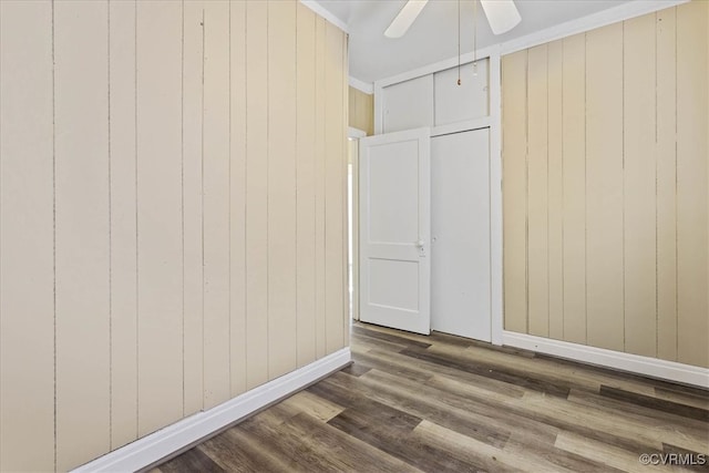 interior space featuring wooden walls, ceiling fan, ornamental molding, and hardwood / wood-style flooring