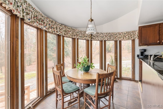 tiled dining room featuring lofted ceiling and sink