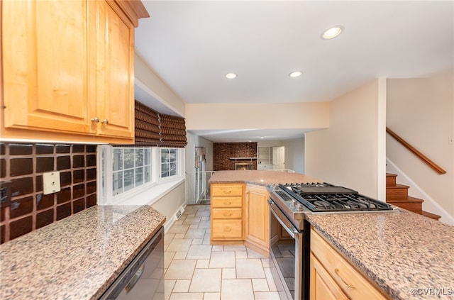 kitchen with light tile patterned floors, stainless steel range with gas cooktop, light stone countertops, and light brown cabinets