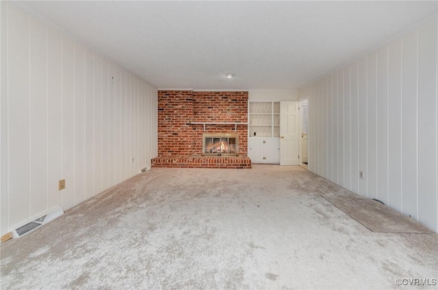 unfurnished living room featuring a brick fireplace, built in features, and carpet