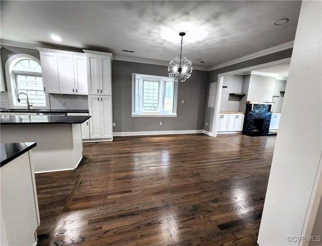 kitchen with sink, hanging light fixtures, dark hardwood / wood-style floors, a fireplace, and white cabinetry