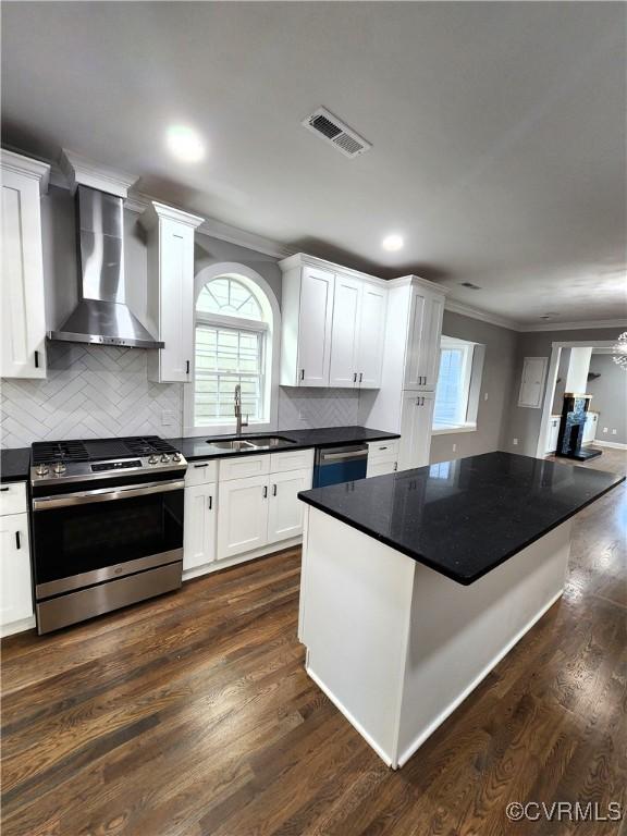 kitchen featuring appliances with stainless steel finishes, wall chimney exhaust hood, dark wood-type flooring, sink, and white cabinets