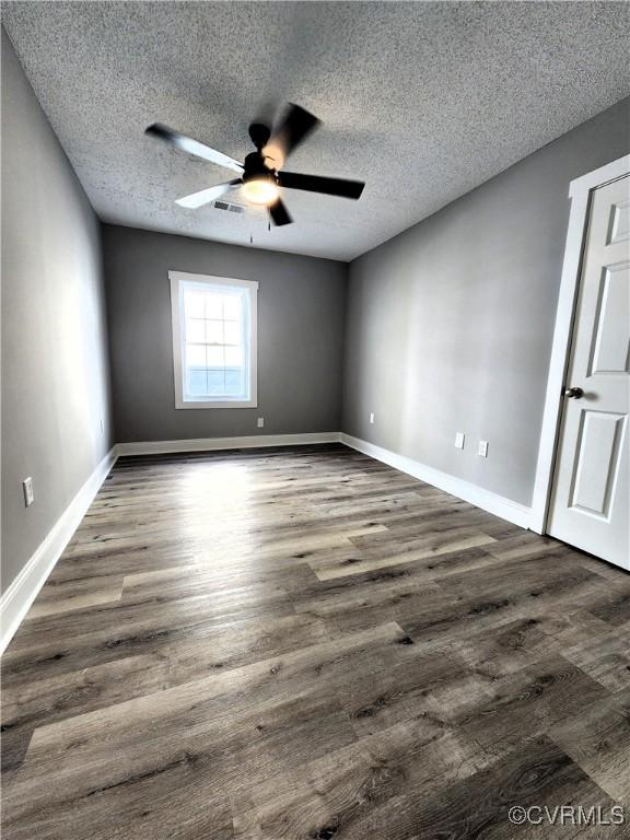 unfurnished room with a textured ceiling, ceiling fan, and dark wood-type flooring