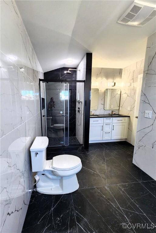 bathroom with vanity, lofted ceiling, toilet, tile walls, and an enclosed shower