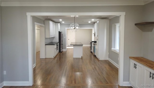 kitchen with crown molding, dark hardwood / wood-style flooring, white cabinets, and decorative light fixtures