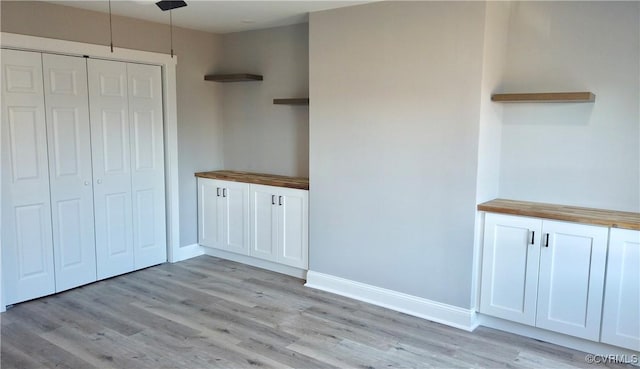 interior space featuring butcher block counters, white cabinets, and decorative light fixtures