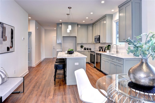 kitchen with gray cabinetry, sink, a center island, pendant lighting, and appliances with stainless steel finishes