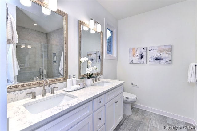 bathroom featuring vanity, hardwood / wood-style flooring, toilet, and a shower with door