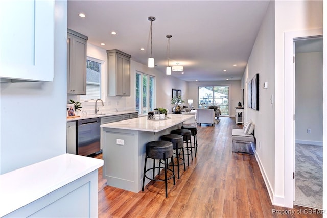 kitchen with stainless steel dishwasher, a breakfast bar, decorative light fixtures, a center island, and gray cabinets