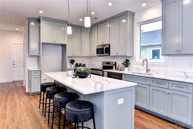 kitchen featuring a center island, stainless steel appliances, light wood-type flooring, and sink