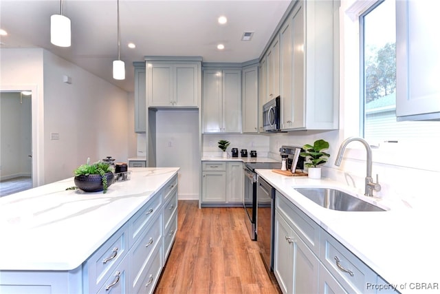 kitchen with sink, stainless steel appliances, light hardwood / wood-style flooring, pendant lighting, and gray cabinets