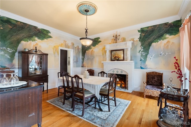 dining space featuring a fireplace, light hardwood / wood-style floors, and ornamental molding