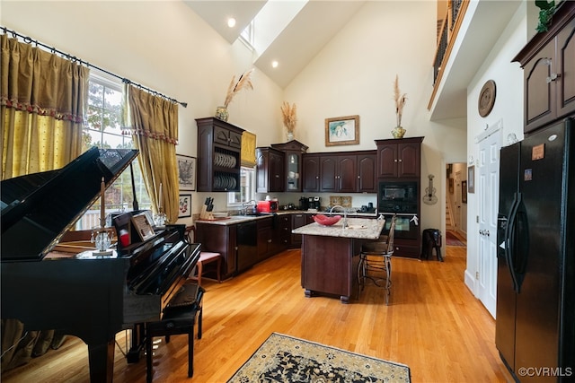 kitchen with black appliances, dark brown cabinets, high vaulted ceiling, sink, and a center island