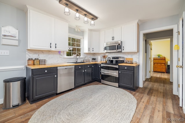 kitchen with stainless steel appliances, wooden counters, hardwood / wood-style floors, white cabinets, and gray cabinets