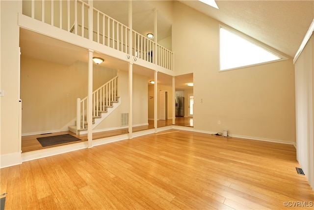 unfurnished living room with hardwood / wood-style flooring and a towering ceiling