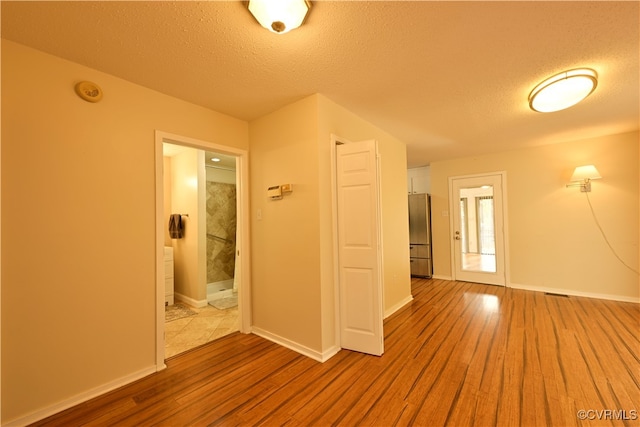 unfurnished room with hardwood / wood-style floors and a textured ceiling