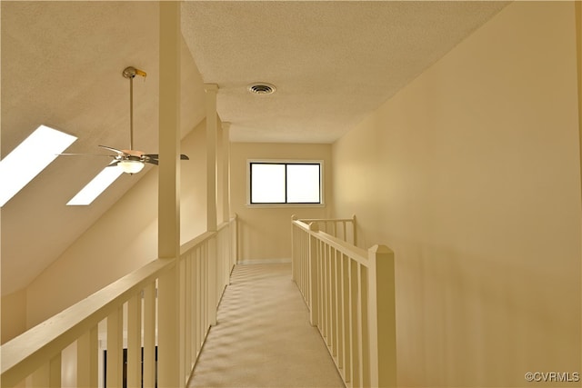 hallway featuring a textured ceiling, light carpet, and a skylight