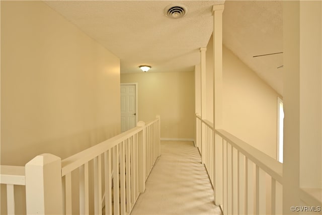 corridor featuring a textured ceiling and light carpet