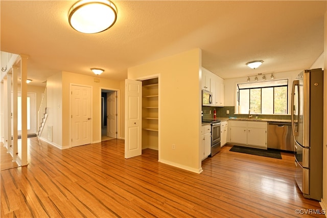 kitchen with light hardwood / wood-style floors, white cabinetry, a textured ceiling, and appliances with stainless steel finishes