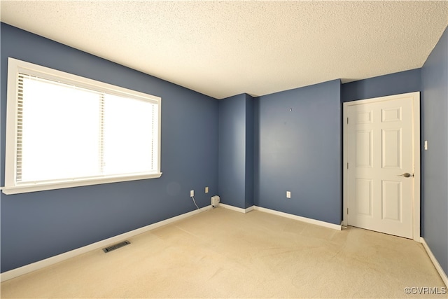 carpeted empty room featuring a textured ceiling