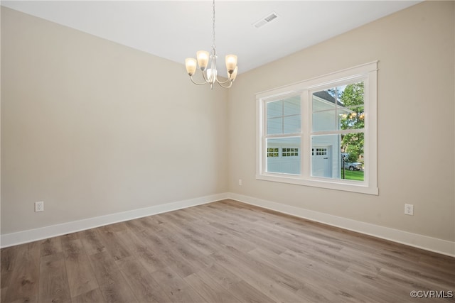 spare room with hardwood / wood-style flooring and a notable chandelier