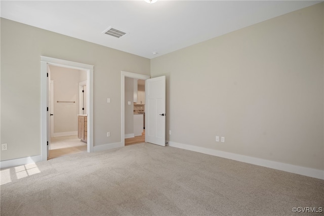 unfurnished bedroom with ensuite bathroom and light colored carpet