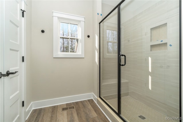 bathroom featuring baseboards, visible vents, wood finished floors, and a shower stall