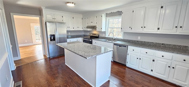 kitchen featuring sink, appliances with stainless steel finishes, light stone counters, white cabinets, and a kitchen island