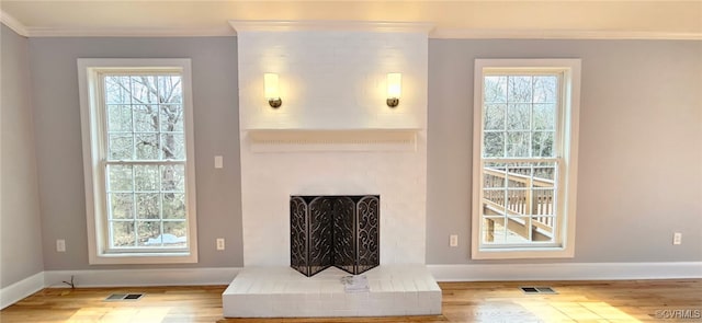 living room with crown molding, plenty of natural light, a fireplace, and hardwood / wood-style flooring