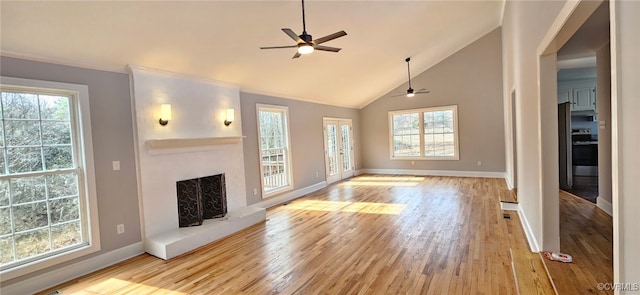 unfurnished living room featuring ceiling fan, a large fireplace, high vaulted ceiling, and light wood-type flooring