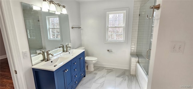 full bathroom featuring vanity, toilet, combined bath / shower with glass door, and a wealth of natural light